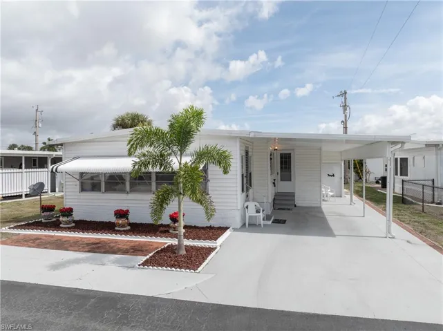 Manufactured / mobile home featuring an attached carport, concrete driveway, and entry steps