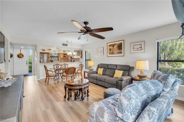 Living / dining room featuring side window, breakfast bar, dining area, new laminate wood-style floor, and ceiling fan