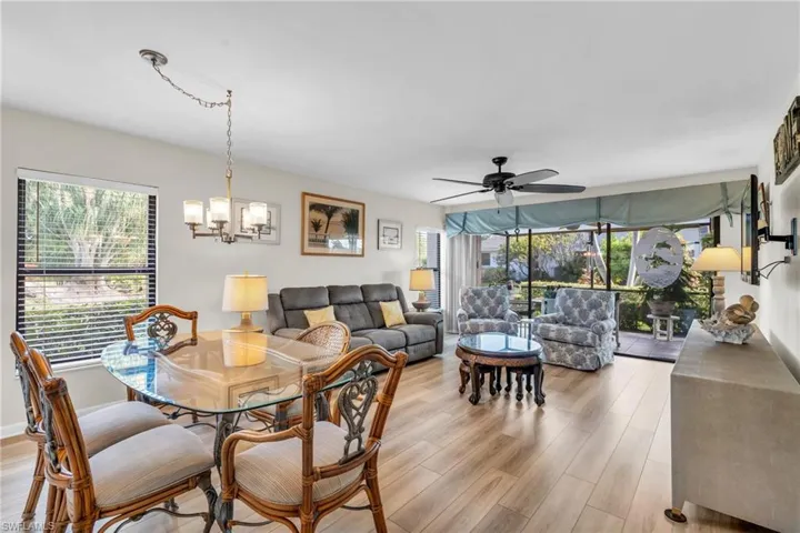 Living / Dining room with chandelier, fan, sliders to lanai, windows, new floors and fresh paint