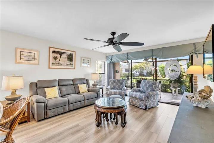 Living room featuring sliding glass doors, new laminate wood-style floor, and ceiling fan