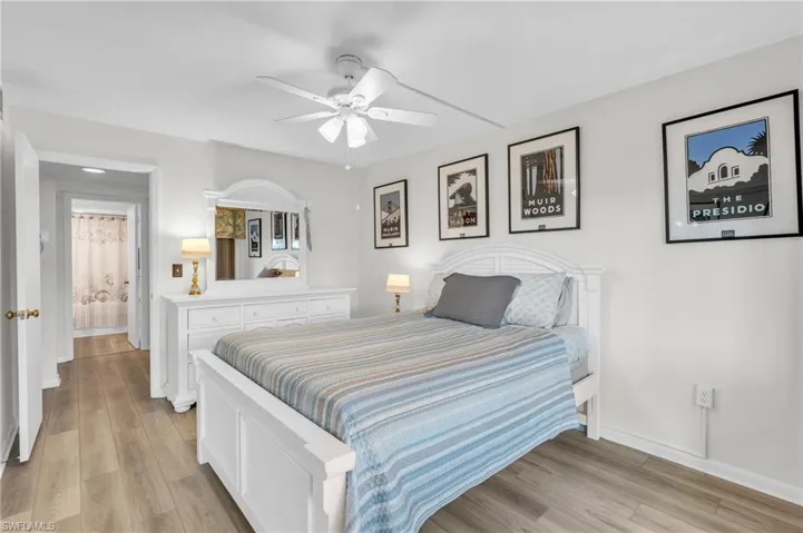 Guest Bedroom featuring bathroom across the hall, new flooring, ceiling fan, spacious closet with mirrors