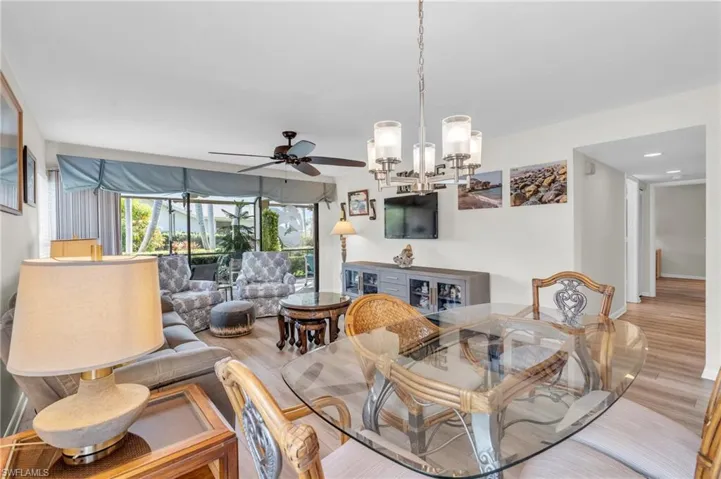 Living room featuring hall to the bedrooms /bathrooms, sliding glass doors, new laminate wood-style floor, and ceiling fan
