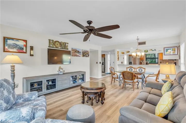 Living / dining room featuring breakfast bar, dining area, new laminate wood-style floor, and ceiling fan