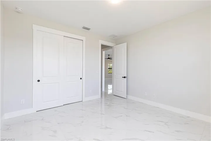 Unfurnished bedroom with light marble finish floors and a closet