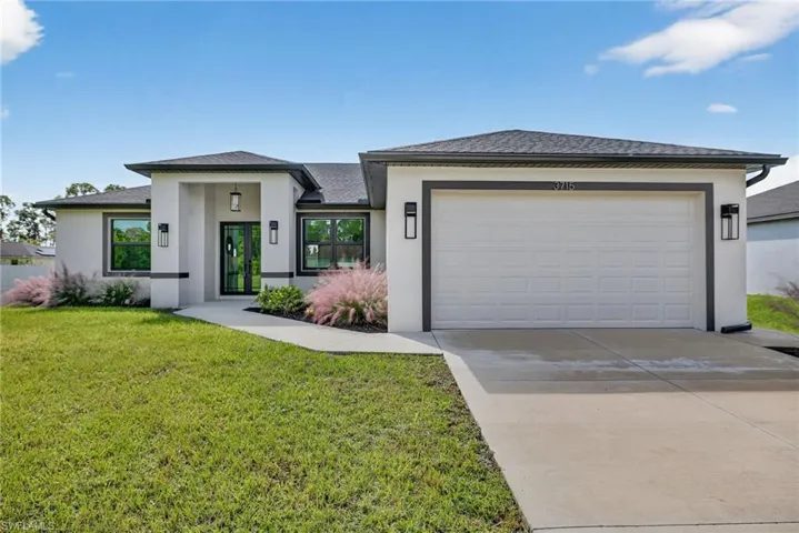 Prairie-style home featuring concrete driveway, a front lawn, stucco siding, an attached garage, and roof with shingles