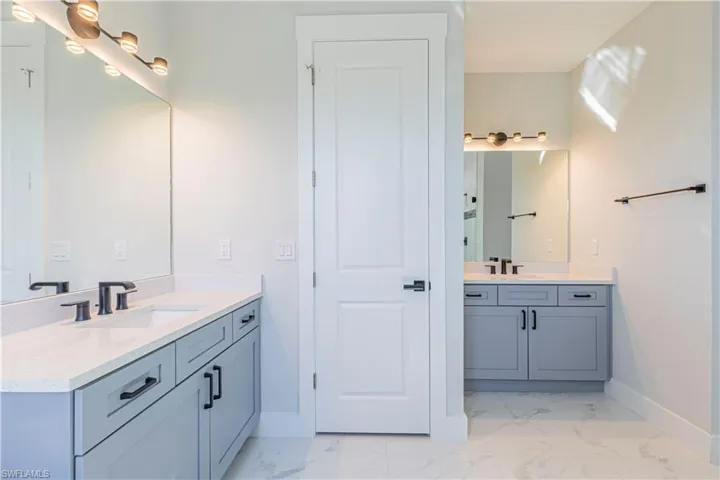 Full bathroom with two vanities and light marble finish floors