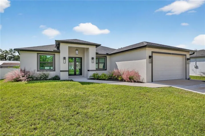 Prairie-style home with stucco siding, a front yard, a garage, and concrete driveway