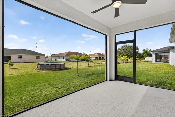 Unfurnished sunroom featuring ceiling fan and a residential view