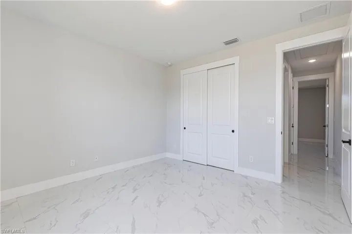 Unfurnished bedroom with light marble finish floors and a closet