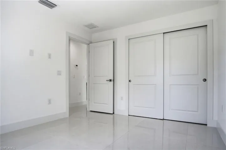 Room featuring bright white walls, contemporary white baseboards, and glossy light-colored tile flooring