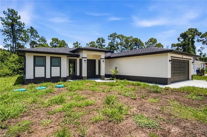 Contemporary exterior featuring a neutral stucco finish, dark trim accents, a prominent covered entry, and a two-car garage