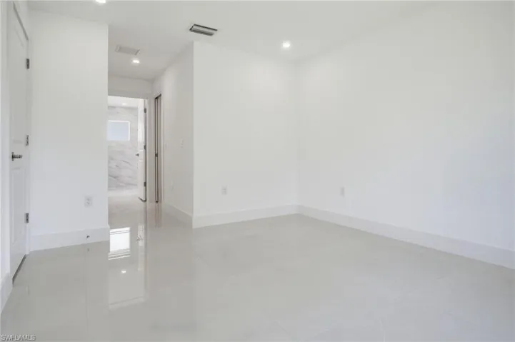 Spacious room featuring light-toned tile flooring, recessed lighting, and a neutral white wall palette