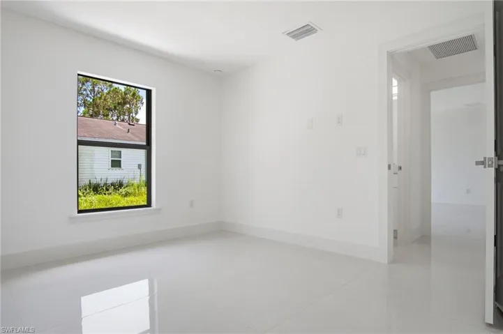 Bright interior room featuring white walls, white baseboards, and a single window with black trim
