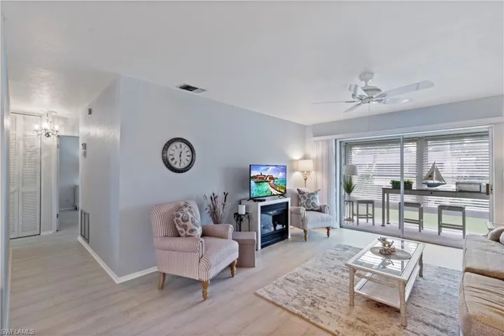 Living room featuring ceiling fan with notable chandelier and light hardwood / wood-style flooring