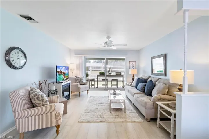 Living room featuring light wood-type flooring, a healthy amount of sunlight, and ceiling fan