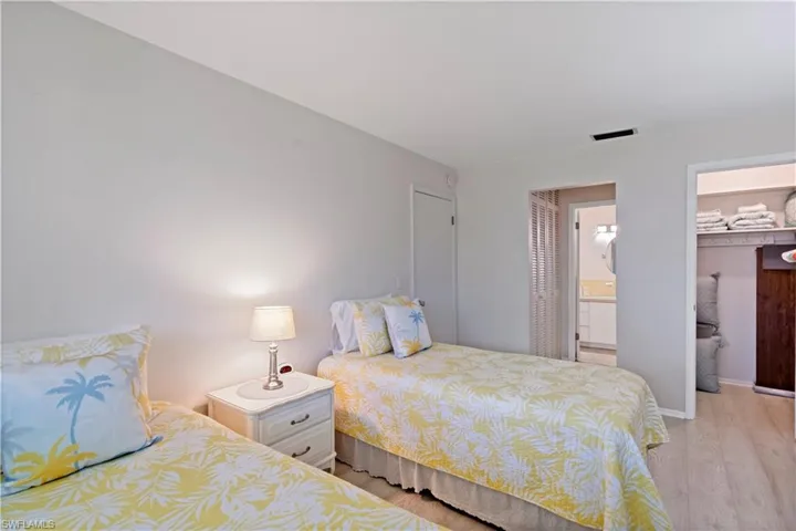 Bedroom with ensuite bath, a closet, a spacious closet, and light hardwood / wood-style floors