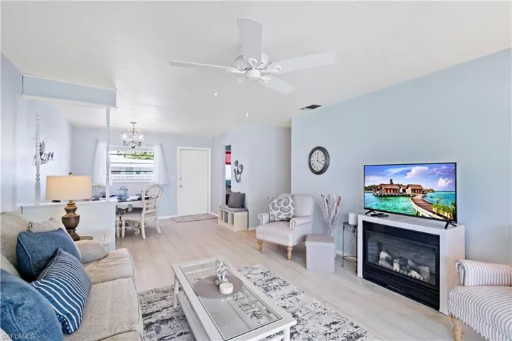 Living room featuring ceiling fan with notable chandelier and light hardwood / wood-style floors