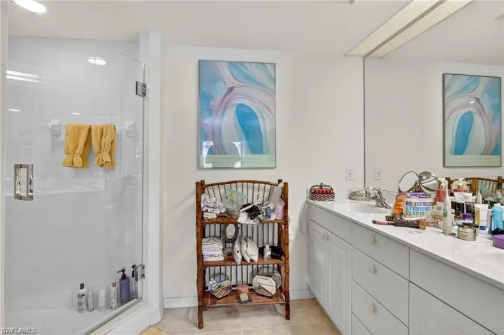 Bathroom with a shower stall, double vanity, and light tile patterned flooring
