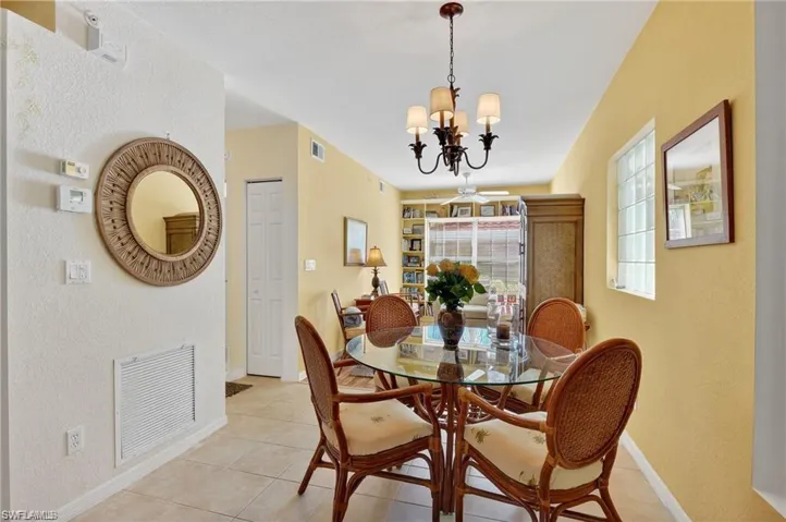 Dining area featuring a textured wall, tile patterned flooring, and a chandelier