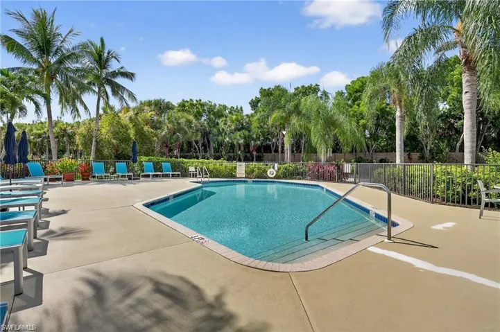 Community pool with a patio area and view of wooded area