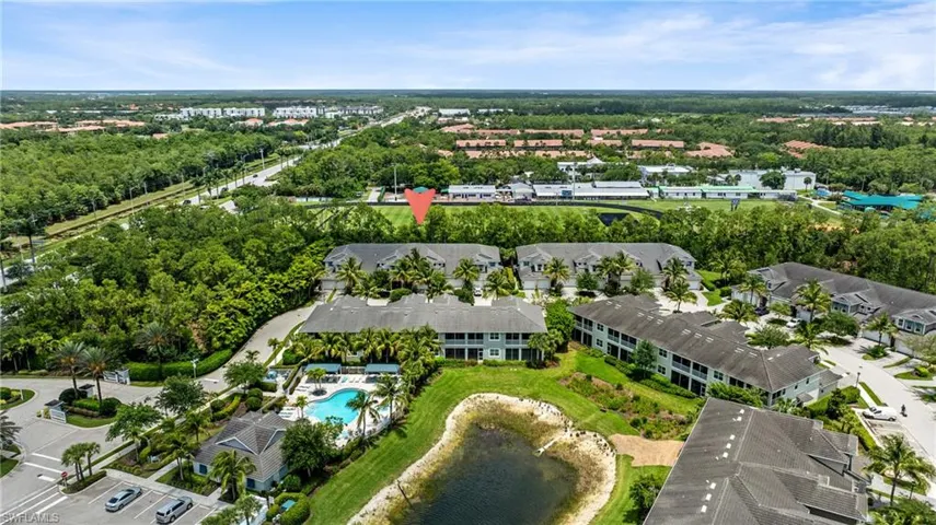 Aerial perspective of a multi-building residential complex featuring a central swimming pool and adjacent recreational building