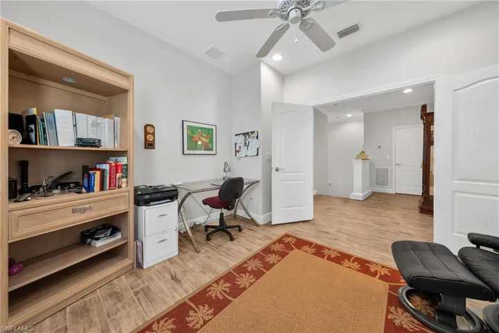 Spacious room featuring wood-finish flooring, light grey wall paint, and a ceiling fan with integrated lighting