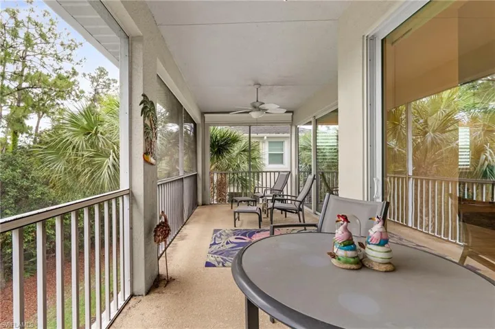 Screened balcony featuring a ceiling fan, concrete flooring, sliding glass doors, and white railing