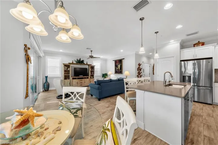 Open concept living area featuring a kitchen island with dual sinks, wood-finish flooring, recessed lighting, and a screened lanai