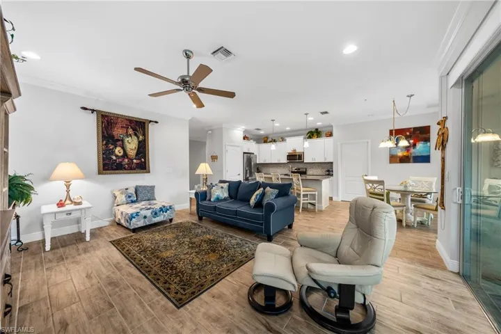 Open-concept living space featuring wood-finish flooring, a ceiling fan, recessed lighting, and sliding glass doors