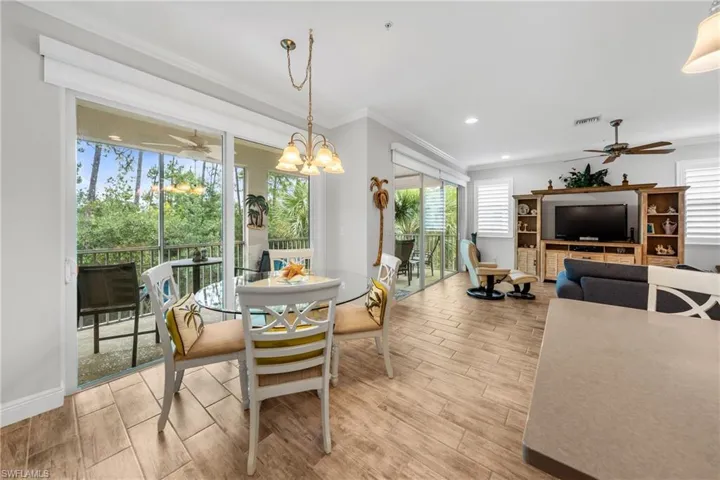 Open-concept living area with wood-finish flooring, a contemporary chandelier, and direct access to a screened balcony