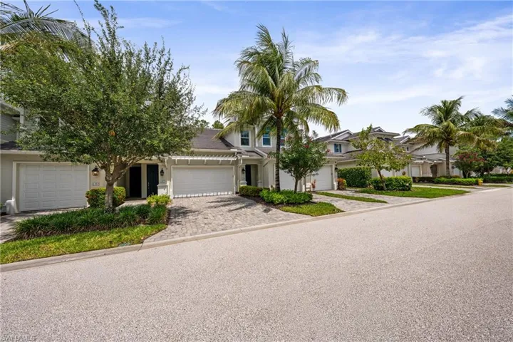 Residential street featuring multiple properties with two-story facades, paver driveways, and integrated garages