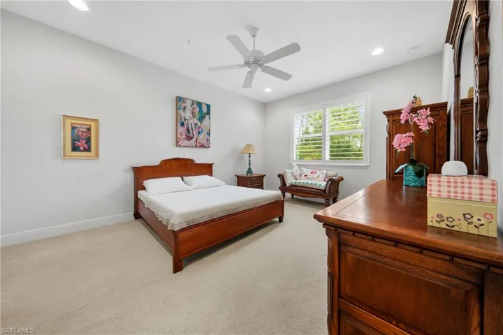Carpeted interior room featuring recessed lighting, a ceiling fan, and a window with plantation shutters