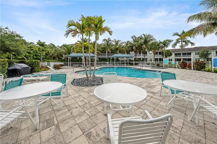 Expansive paver patio surrounding a blue-tiled swimming pool