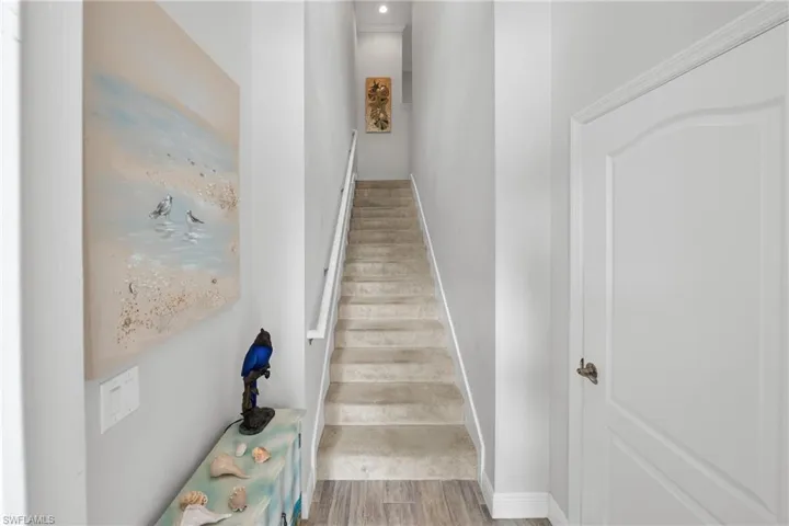 Carpeted staircase with white handrail, recessed lighting, and wood-finish flooring