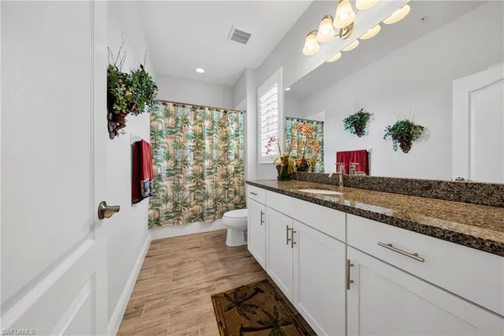 Bathroom featuring a double vanity with white cabinetry and a speckled countertop