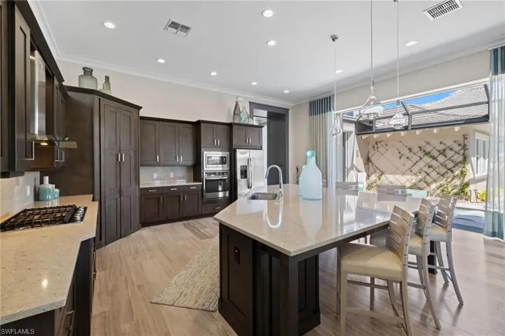 Gourmet kitchen with dark wood cabinetry, light-toned countertops, and integrated stainless steel appliances