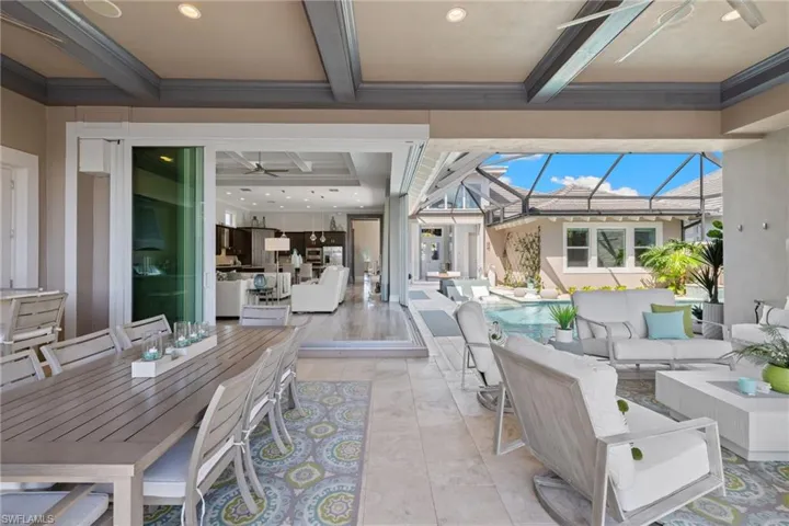 Expansive covered lanai featuring a coffered ceiling with recessed lighting, large format tile flooring, and integrated screen enclosure