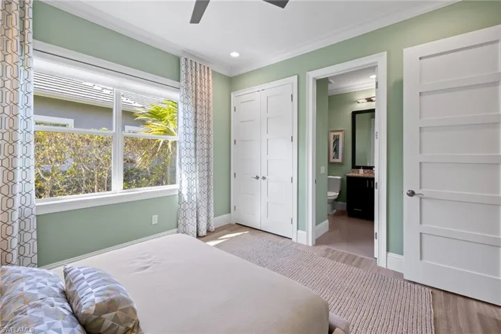 Bedroom #2 featuring a large four-pane window, light green walls, a ceiling fan, and two white five-panel doors