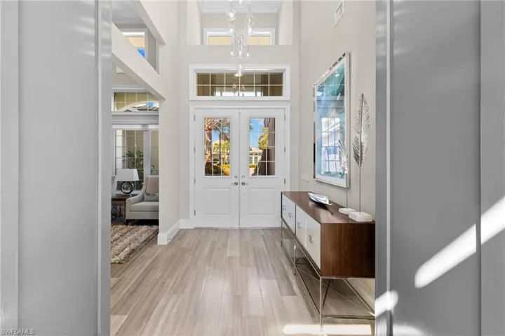 Foyer featuring double entry doors with glass panels, a transom window, and a grand chandelier