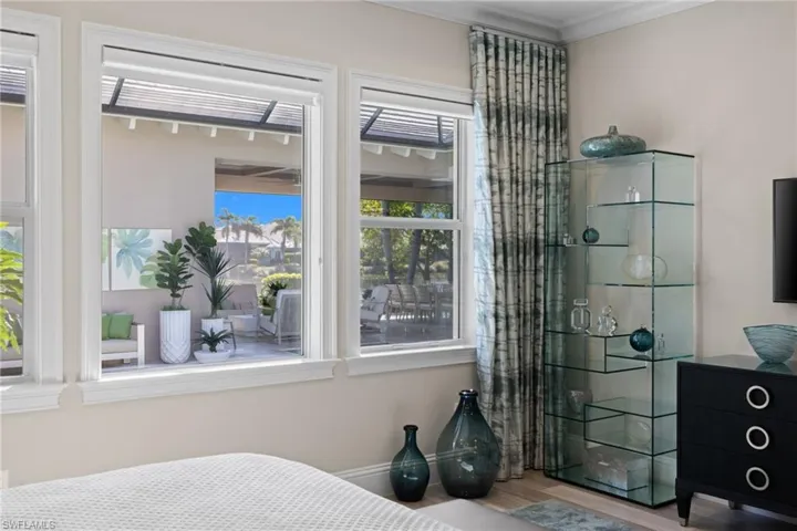 Primary bedroom #1, featuring multiple windows with white trim, offering a bright interior and a patio beyond