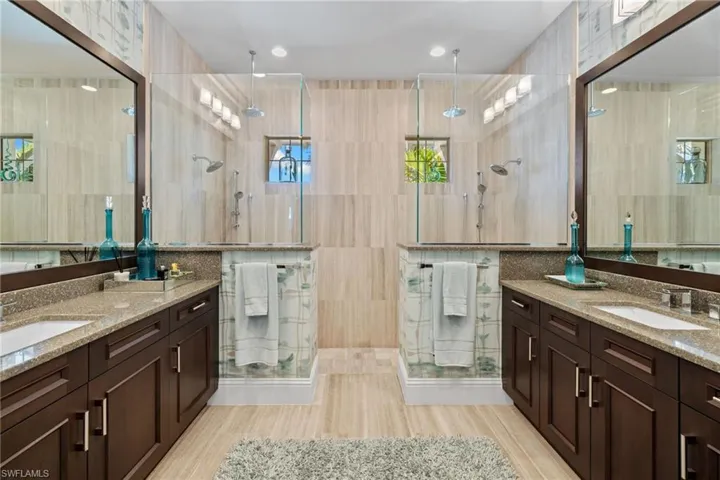 Primary bathroom #1, featuring dual walk-in showers with glass enclosures and dual shower heads