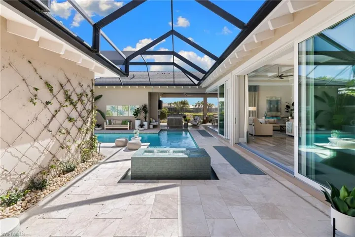 Screened outdoor living area featuring a rectangular pool and integrated spa
