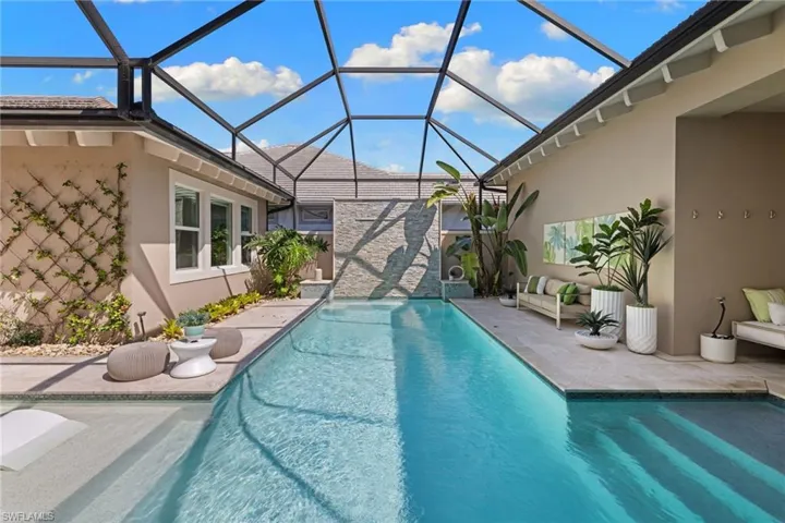 Screened-in lap pool featuring a sun shelf entry