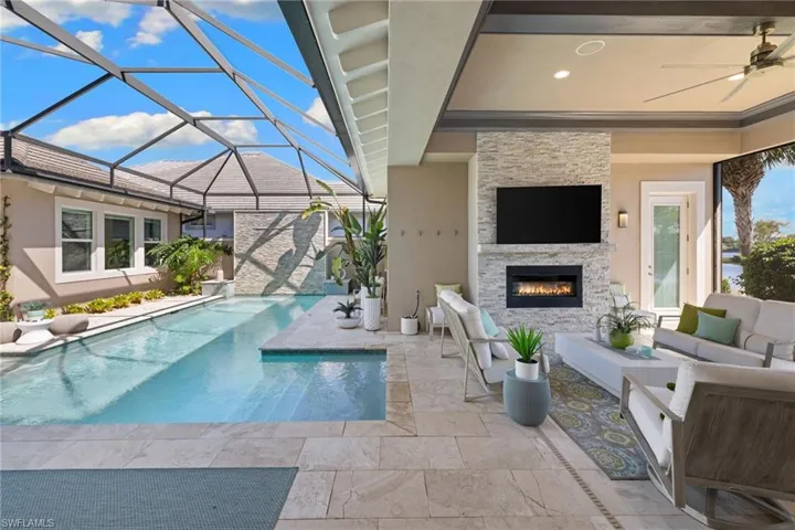 Screened-in outdoor living space featuring a swimming pool with integrated spa and a covered patio with a stacked stone fireplace
