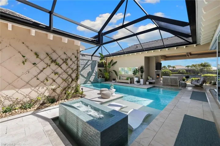 Screened outdoor living area featuring a rectangular pool with integrated sun shelf and spa