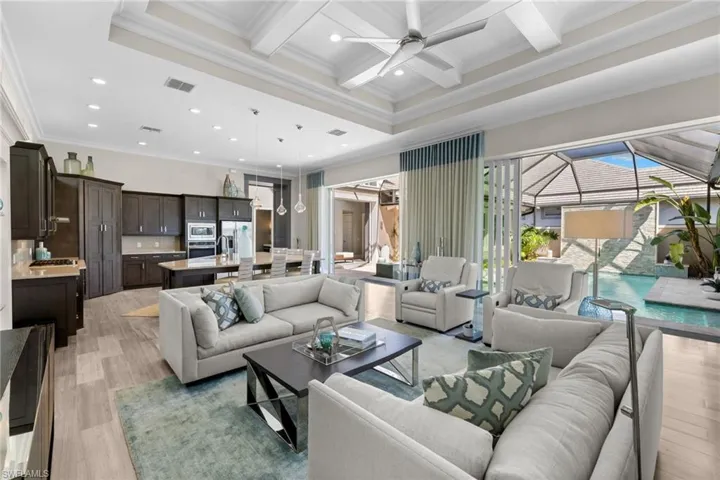 Expansive open-concept living area featuring a coffered ceiling with a flush-mount fan, plank-style flooring, and recessed lighting