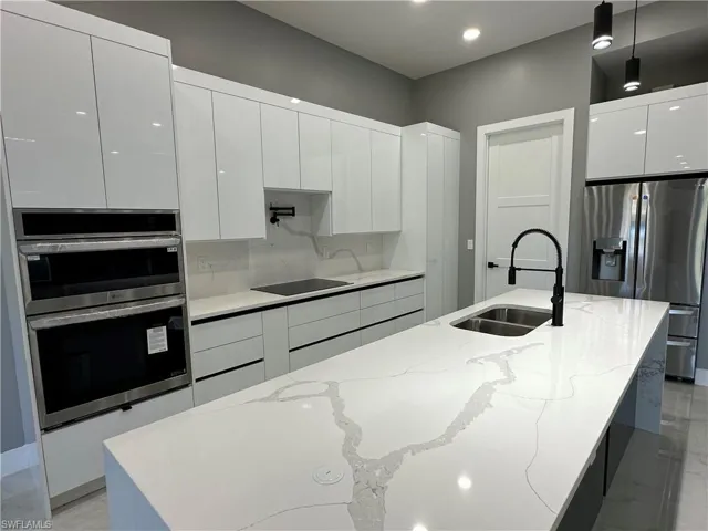 Kitchen featuring pendant lighting, stainless steel appliances, sink, and an island with sink
