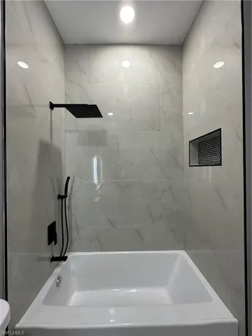 Bathroom with tiled shower / bath and toilet