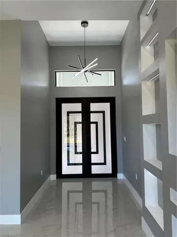 Entryway with plenty of natural light, a towering ceiling, a notable chandelier, and french doors