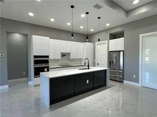 Kitchen featuring white cabinetry, sink, a kitchen island with sink, and appliances with stainless steel finishes